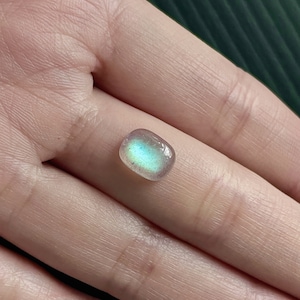 May include: A light blue oval-shaped labradorite gemstone with iridescent flashes of colour.