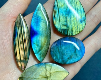 May include: Five iridescent labradorite gemstone cabochons in various shapes and sizes. The stones are a mix of blue, green, and gold.