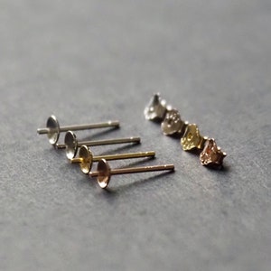 May include: Four pairs of earring posts with different coloured tops. The posts are silver and the tops are silver, gold, and rose gold.