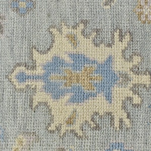 May include: Close-up of a light blue rug with a cream and gray geometric pattern. The rug has a soft, textured surface.