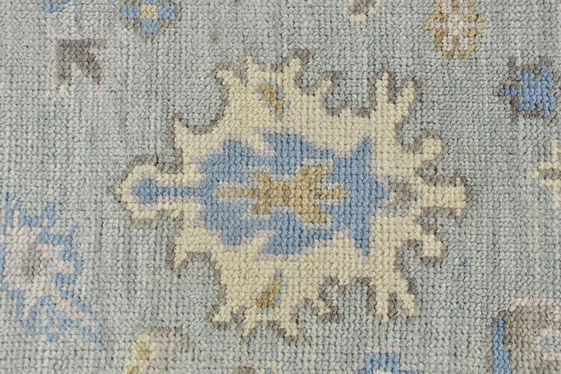 May include: Close-up of a light blue rug with a cream and gray geometric pattern. The rug has a soft, textured surface.