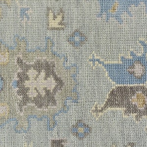 May include: A close-up of a light blue rug with a geometric pattern in shades of blue, gray, and beige.