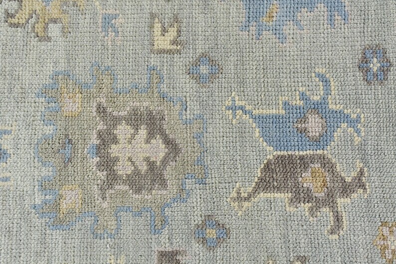 May include: A close-up of a light blue rug with a geometric pattern in shades of blue, gray, and beige.