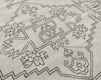 May include: A gray rug with a black geometric pattern. The pattern features stylized flowers and a central cross shape. The rug has a subtle texture and a distressed look. The text "DreamrugsIndia" is visible in the lower right corner.