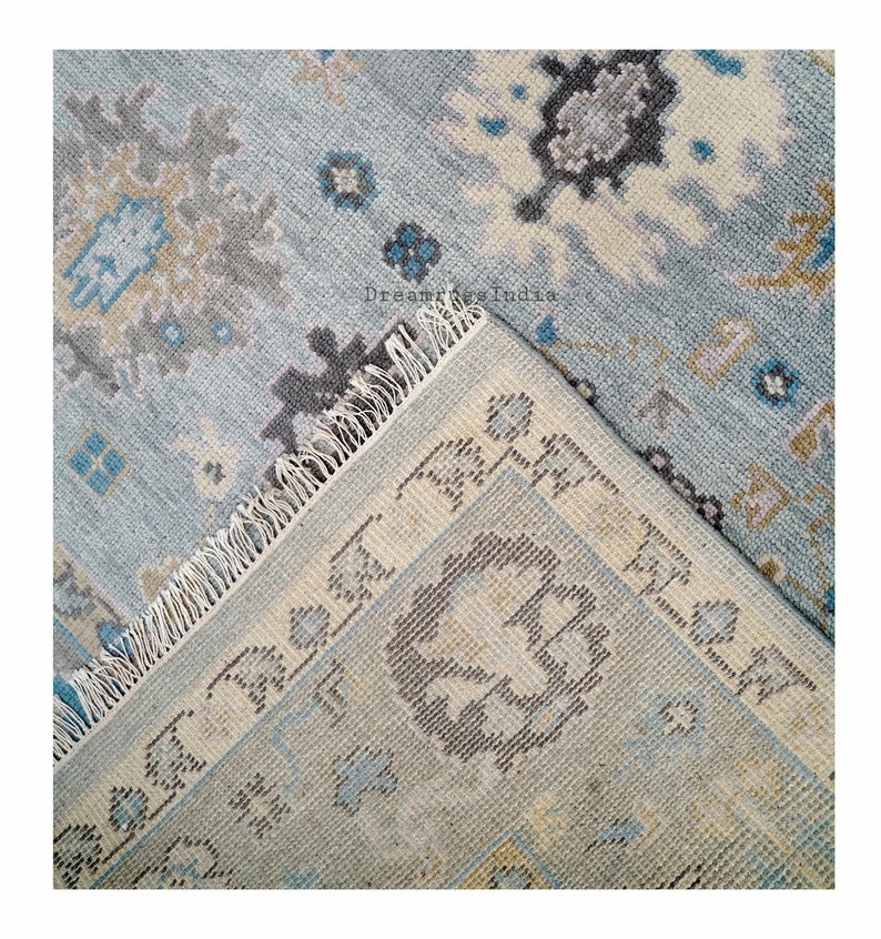 May include: Close-up of a blue and cream patterned rug with fringed edges. The rug has a traditional design with floral motifs.