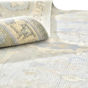 May include: A light blue rug with a subtle pattern of white and beige. The rug is rolled up, showing the edge of the rug with a more detailed pattern.