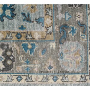 May include: A blue and gray patterned rug with a floral design. The rug has a fringe border.