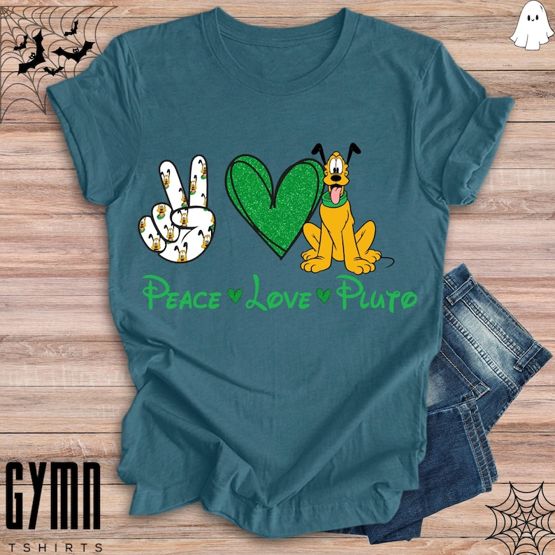 Pode incluir: Uma camiseta azul turquesa com um s&iacute;mbolo de paz verde, um cora&ccedil;&atilde;o verde e uma imagem de desenho animado do Pluto. O texto "Peace Love Pluto" est&aacute; impresso na camiseta.