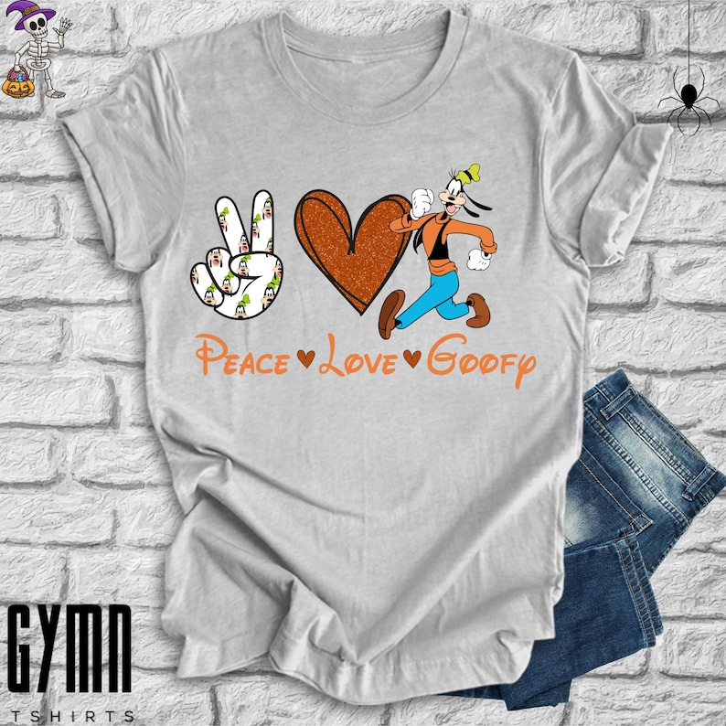 Pode incluir: Uma camiseta cinza com um sinal de paz, um cora&ccedil;&atilde;o e uma imagem de desenho animado do Pateta correndo. O texto "Peace Love Goofy" est&aacute; impresso na camiseta.