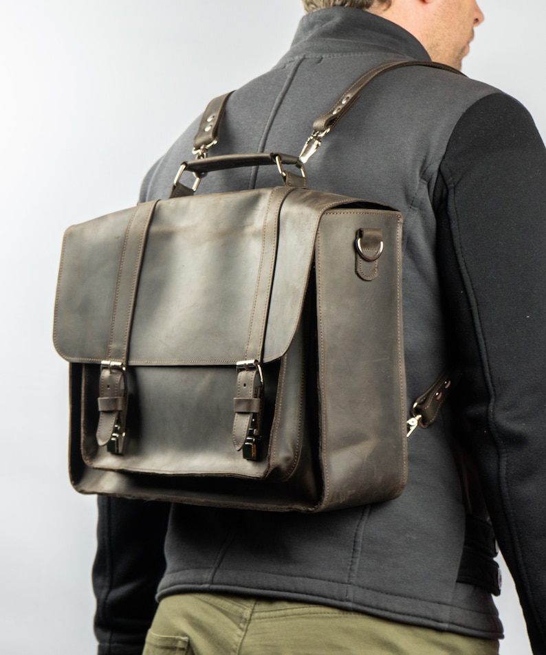 Peut inclure: Un sac &agrave; dos en cuir marron avec des bretelles r&eacute;glables et des boucles. Le sac a une poign&eacute;e sup&eacute;rieure et une fermeture &agrave; rabat.