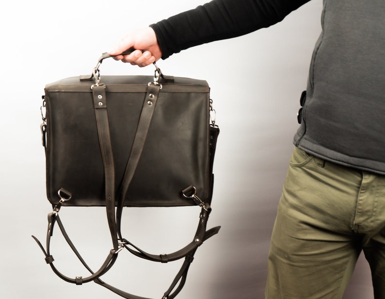 Peut inclure: Une mallette en cuir marron avec des bretelles r&eacute;glables qui peuvent &ecirc;tre port&eacute;es comme un sac &agrave; dos. Le sac a une poign&eacute;e sup&eacute;rieure et une poche avant.