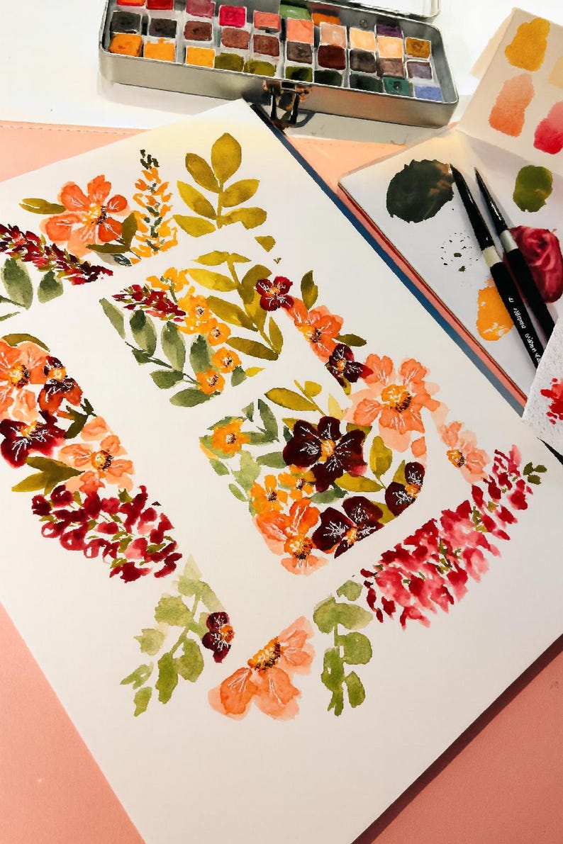 May include: Watercolor floral art on white paper, featuring orange, red, and burgundy flowers with green leaves. A metal watercolor paint set and paintbrushes are visible, suggesting a painting theme.