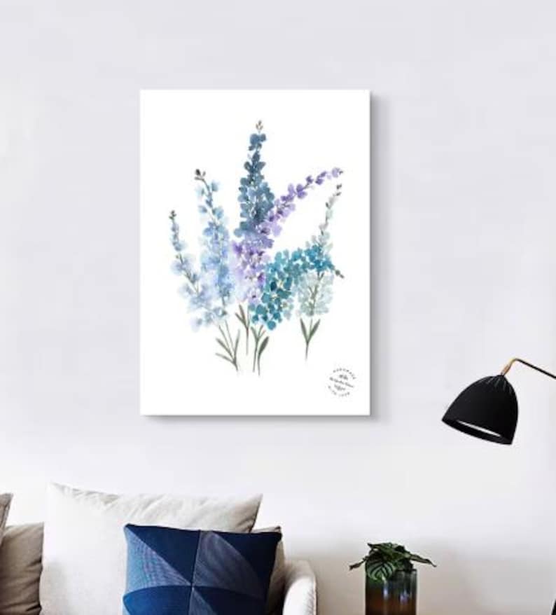 May include: Watercolor painting of blue and purple flowers on a white background. The artwork features a bouquet of delicate blooms with green stems. The painting is displayed on a white canvas, perfect for home decor.