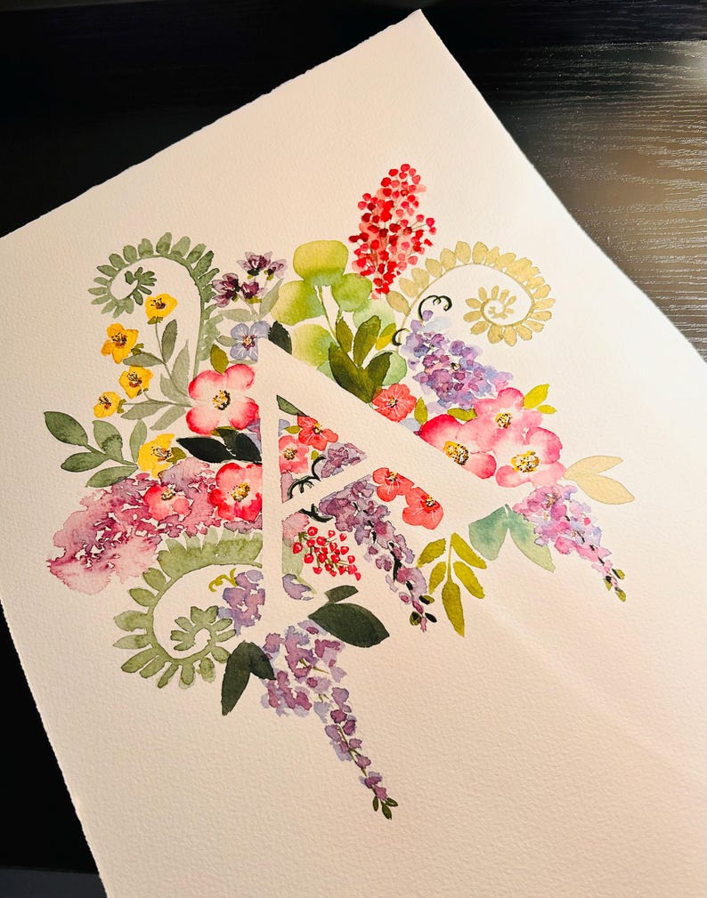 May include: Watercolor painting of the letter A surrounded by a variety of flowers in shades of pink, purple, yellow, and green.