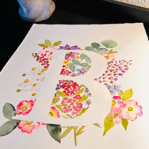 May include: A watercolour painting of the letter "R" formed from pink, white, purple and yellow flowers. The flowers are arranged to create the shape of the letter.