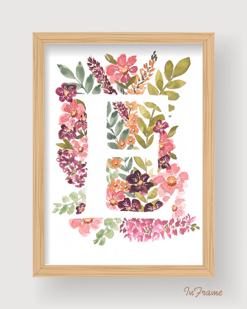 Pu&ograve; includere: Una stampa ad acquerello incorniciata con la lettera "E" circondata da fiori e fogliame colorati. La composizione floreale include fiori rosa, viola e arancioni con foglie verdi. La cornice &egrave; in legno chiaro e il testo "In Frame" &egrave; in basso a destra.