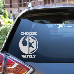 May include: A white vinyl sticker with a Star Wars themed design. The sticker features the Rebel Alliance symbol and the Imperial symbol, with the text "CHOOSE WISELY" below.