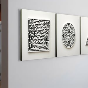 May include: Three white framed wall art pieces with black and white maze designs. The shapes include a rectangle, a circle, and a triangle. The art is mounted on a light gray wall.