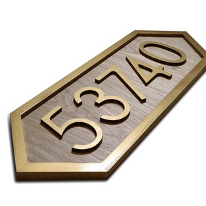 May include: Wooden address sign with gold-colored numbers and a gold border. The numbers read 53740. The sign has a light brown wood grain background and is in a unique pentagon shape.