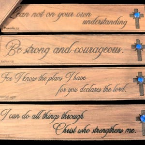 May include: Four wooden bookmarks with blue gemstone crosses and inspirational bible verses. The verses are: "Lean not on your own understanding", "Be strong and courageous", "For I know the plans I have for you declares the Lord", and "I can do all things through Christ who strengthens me".
