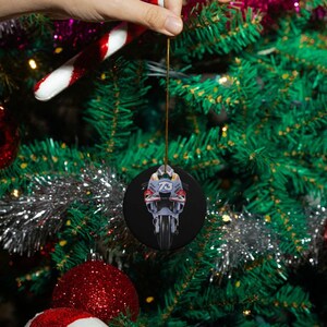 May include: A round Christmas ornament featuring a black and white image of a motorcycle with the number 76 on the side.