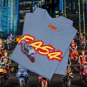 May include: A light blue t-shirt with a motorcycle graphic and the word "F454" in yellow and red. The shirt also features the text "CMM" in orange. The background includes a cityscape and motorcycle racers.