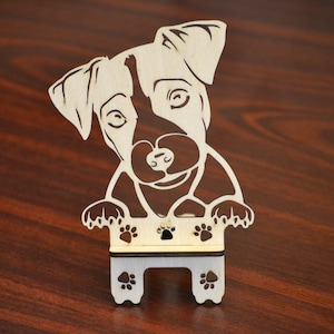以下が含まれることがあります： 木製の犬型装飾品。犬は明るい茶色の顔に濃い茶色のアクセントと足跡があります。このアイテムは明るい色の木材で作られており、切り抜きデザインになっています。