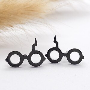 Könnte beinhalten: Ein Paar schwarze Ohrstecker in Form von Harry Potters Brille mit einem Blitzdetail.