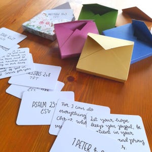 Met de hand getekende bijbelverzen in een klein doosje ~ 10 themaverzen in een gewatteerde kaartenvelop van 7 x 7,5 x 1 cm.  Kalligrafieschrift, christelijk cadeau.