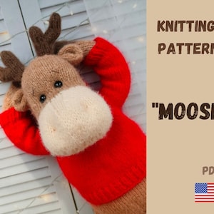 May include: A knitted moose toy wearing a red sweater, with brown antlers and a cream snout. The image includes the text "KNITTING PATTERN" and "MOOSE". The PDF pattern is indicated with the American flag.