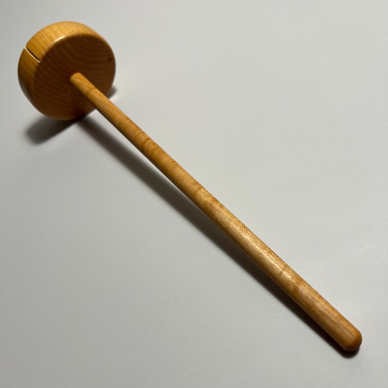 Pu&ograve; includere: Un rocchetto di legno con una parte superiore circolare e un lungo manico sottile. La venatura naturale del legno &egrave; visibile. Progettato per contenere il filo per progetti di maglia o uncinetto.