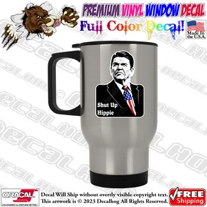 May include: A silver travel mug with a black handle and lid. The mug features a black and white image of a man with the text "Shut Up Hippie".