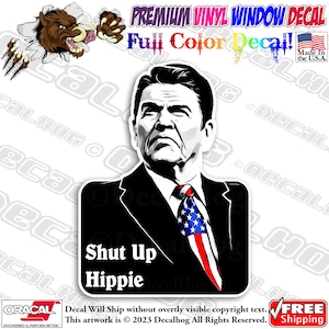 May include: A black and white illustration of a man with a serious expression. He is wearing a suit and tie with an American flag pattern. The text "Shut Up Hippie" is printed below the image.