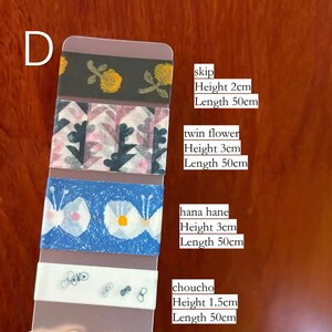 Könnte beinhalten: Eine Sammlung dekorativer Washi-Tapes mit Blumen- und Schmetterlingsmotiven. Die Tapes sind in verschiedenen Farben erhältlich, darunter Blau, Weiß und Schwarz. Jedes Tape ist 50 cm lang, mit Höhen von 1,5 cm bis 3 cm.