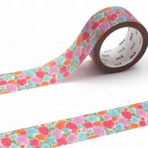 May include: A roll of decorative washi tape with a floral pattern. The tape features a repeating design of pink, orange, and blue flowers and leaves on a light green background. The tape is partially unrolled, showing the pattern.