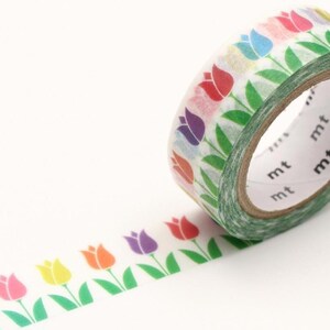 Könnte beinhalten: Eine Rolle dekoratives Washi-Tape mit einem sich wiederholenden Muster aus bunten Tulpen. Die Tulpen sind in Rosa, Gelb, Orange, Lila und Rot gehalten, mit grünen Blättern und Stielen. Das Klebeband ist weiß und trägt den Aufdruck "mt".