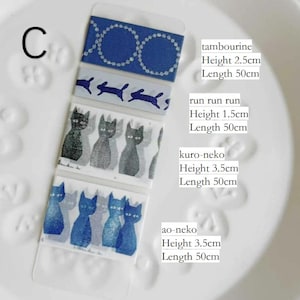 Könnte beinhalten: Eine Auswahl an dekorativen Washi-Tapes mit verschiedenen Designs. Enthält blaue Tapes mit weißen Kreisen, Kaninchensilhouetten, Katzenillustrationen und blauen Katzenmotiven. Jedes Tape ist 50 cm lang.