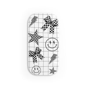 May include: A white rectangular object with a grid pattern, featuring black and white checkered bows, stars, lightning bolts, and smiley faces. The design is repeated across the surface.