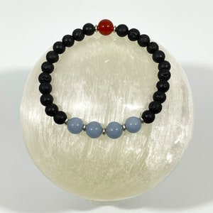May include: A black lava rock bracelet with a red carnelian bead and four blue agate beads.