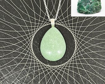 May include: A light green teardrop-shaped pendant necklace with a silver chain. The pendant is smooth and polished. A rough green stone is in the upper right corner. The background is black with a white geometric design.