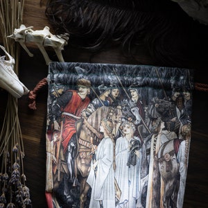 Pode incluir: Uma bolsa de cordão com um exterior de tecido verde e preto. A bolsa apresenta uma imagem impressa de uma cena medieval com cavaleiros a cavalo e damas com túnicas brancas.