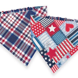 May include: Two patriotic dog bandanas. One features a red, white, and blue plaid pattern. The other is a patchwork design with stars, stripes, and hearts. Both have a ruffled edge.