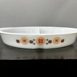 May include: White oval divided baking dish with brown and orange geometric designs around the rim.