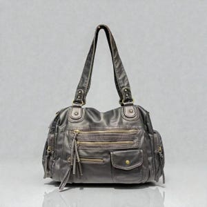 May include: A dark gray handbag with multiple zippered compartments and pockets. The bag has two handles and gold-colored zippers and hardware. The material appears to be faux leather.