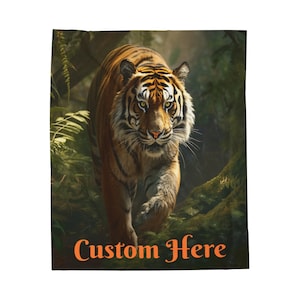 May include: A blanket featuring a detailed image of a tiger walking through a lush green forest. The tiger has orange and black stripes. The text "Custom Here" is printed in orange at the bottom of the blanket.