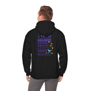 Puede incluir: Sudadera con capucha negra con un estampado gráfico morado y blanco que dice "5 cosas que debes saber sobre tu asistente médico". El gráfico incluye una mariposa azul y flores amarillas.