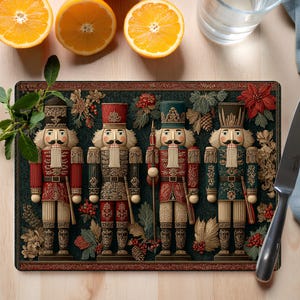 May include: A rectangular cutting board featuring four detailed nutcracker figures in red, green, and gold uniforms. The board has a dark green background with floral and pinecone accents. Oranges and a glass of water are visible.