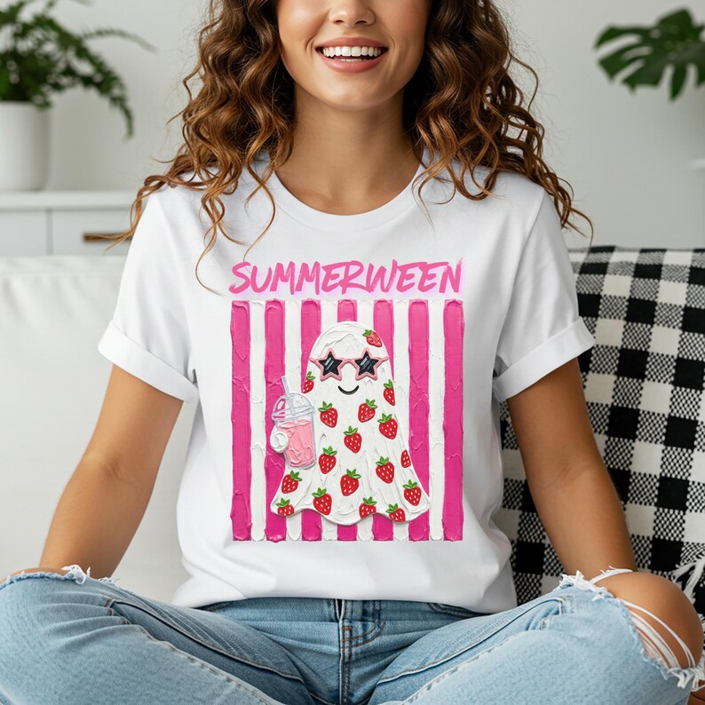 May include: White t-shirt with the word "SUMMERWEEN" in pink above a ghost illustration. The ghost wears sunglasses and is covered in strawberries, holding a pink drink. Pink vertical stripes are behind the ghost.