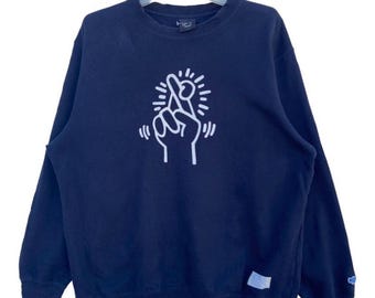 Sudadera vintage de Keith Haring Uniqlo con cuello redondo, estampado gráfico de dedos cruzados en azul marino, estilo urbano unisex.
