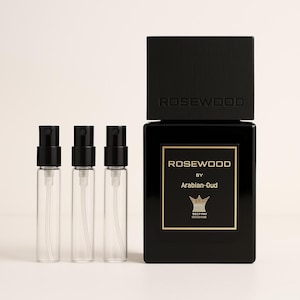 May include: Three small clear glass spray bottles with black caps and a larger black bottle with a gold label that reads "Rosewood by Arabian-Oud".